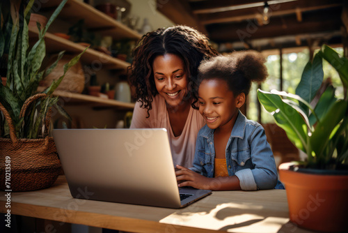 Happy African American Mother and Daughters Learning and Smiling Together Indoors, Reading and Bonding via Laptop