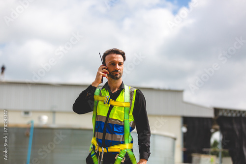 A Professional engineer or expert technician using radio communication or walkie-talkie to order work, control, advice or explain situation to employees in outdoor solar panel farm renewable energy.