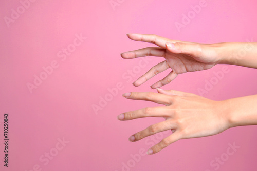 Two female's hands trying to grab or reach something isolated over pink background