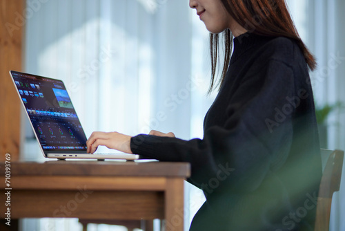 ノートパソコンにて動画編集を行うクリエイターの日本人女性