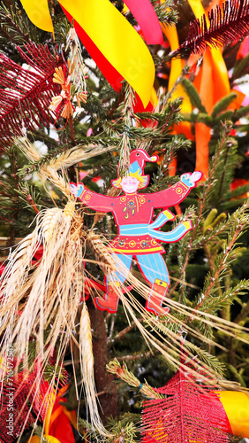 Moscow seasons. Decorations in honor of the celebration of the traditional Russian holiday Maslenitsa (Shrovetide). An image of a petrushka toy on a Christmas tree with multicolored ribbons.