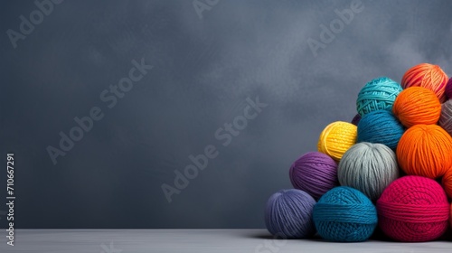 Rainbow wool yarn balls on gray background with ample text space for design or advertising.