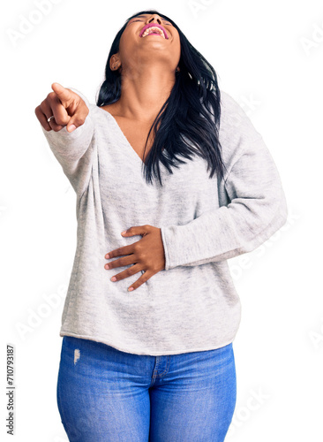 Hispanic woman with long hair wearing casual clothes laughing at you, pointing finger to the camera with hand over body, shame expression