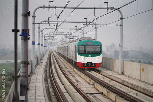 Dynamic shot of the Dhaka Metro Rail gracefully gliding along the tracks, symbolizing progress, modernity, and efficient urban transportation in the vibrant cityscape of Dhaka, Bangladesh.