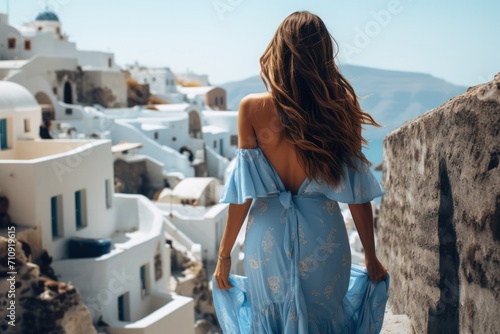 beautiful attractive brunette woman in blue dress on a Greek island on sunny day with sea view and white buildings. Travel agency banner and tourism. Solo female traveler. Fashion and style.