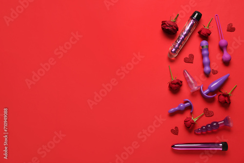 Composition with beautiful rose flowers and different sex toys on red background