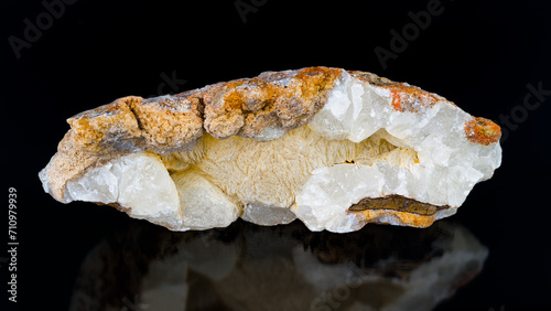 Closeup a mineral stone aragonite on black background with reflection. Calcium carbonate. Beautiful yellow white orange collectable piece of limestone rock. Origin in Hridelec near Nova Paka, Czechia.