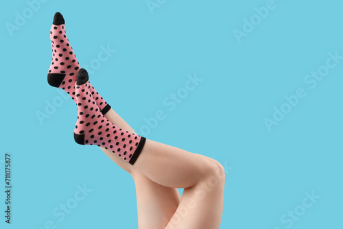 Legs of young woman in socks on blue background