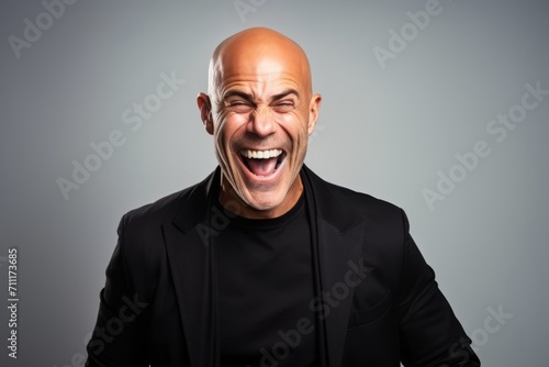 Laughing bald man over grey background. Looking at camera.