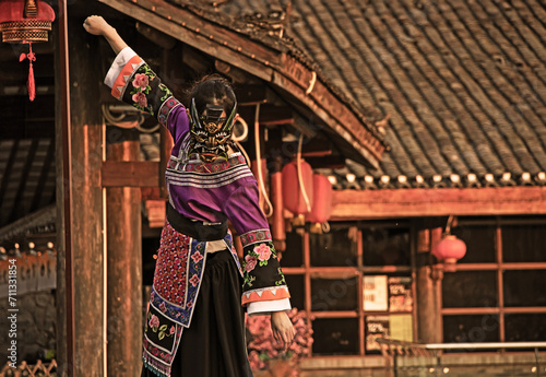 a young girl in a Chinese national dress, wearing a dragon mask, against the background of national buildings of houses, hanging red fanariks