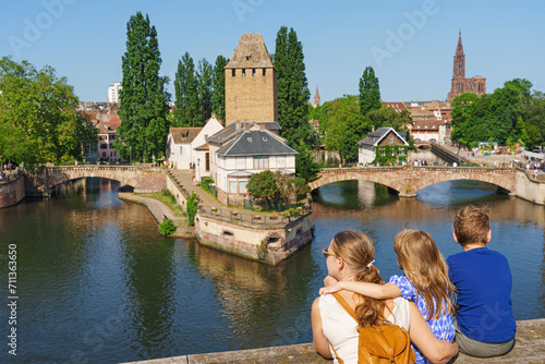 A family of tourists looks on Bridge Ponts Couverts de Strasbourg, Strasbourg, Alsace, France. Canals district La Petite France in Strasbourg in summer.