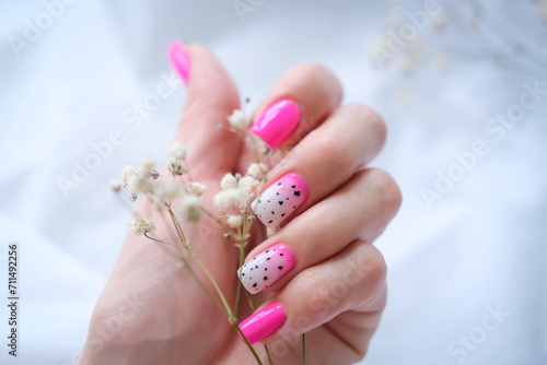 Women's hands with a fashionable pink manicure hold dried flowers in their hands. Spring - summer nail design