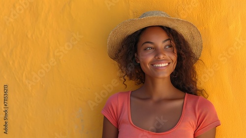 Mujer sonriendo, sombrero de paja, a la sombra, lejos del calor tropical, amarillo mostaza, camiseta cuello redondo, espacio para copy, fondo muro amarillo con textura, felicidad, naturalidad, foto