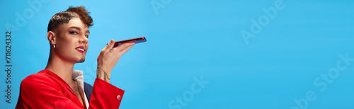 Banner. Male model with masculine and feminine appearance talking on phone against blue background with negative space to insert text. Concept of business, self-expression, delivery, connection. Ad