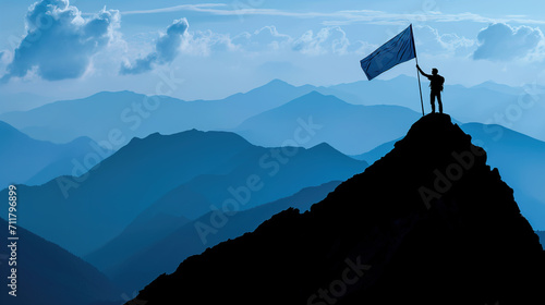 Silhouette of man holding blue flag on mountain top in sign of success and achievement