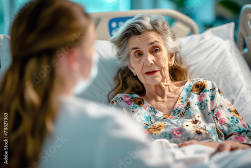 Friendly Professional Female Doctor Meeting An Elderly Patient On A Hospital Bed The Concept Of Caring For The Eldery, Nurse Is Taking Anamnesis From Old Lady.