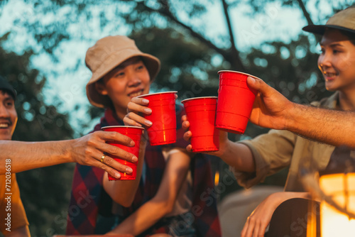 Cheers! Group of asian people friend party camping in nature making toasting with soft drink and beer red cup. Hangout party outdoor in campsite nature forest background on holiday weekend vacation