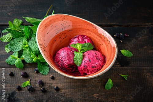 Ice cream berry sorbet made from blackcurrant and mint. Menu for a restaurant. Beautiful composition on wooden boards.