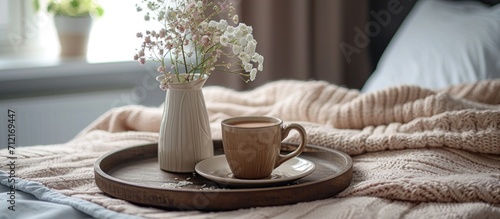 a tray containing coffee and a flower arrangement on top of a bed