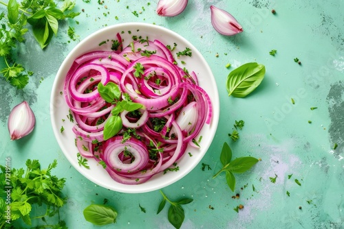 Healthy fermented food Top down view of pickled red onion rings fresh herbs white bowl Green background