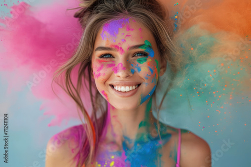 Smiling adult girl celebrating Holi festival in India, portrait of happy young woman with paint on face, female on colorful powder background. Concept of color, party, fun, travel