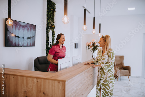 A beautiful blonde woman conversing with the dental clinic receptionist, scheduling an appointment for dental treatment with a bright smile