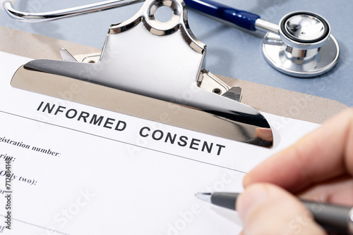 Hand filling a Informed Consent form on desk