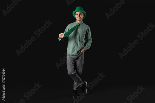 Happy young man in green leprechaun's hat on dark background. St. Patrick's Day