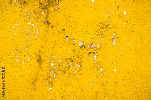 Grunge old concrete wall painted in bright yellow with cracks. Abstract texture, background