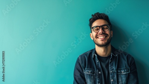 Cheerful man in denim jacket against a turquoise background