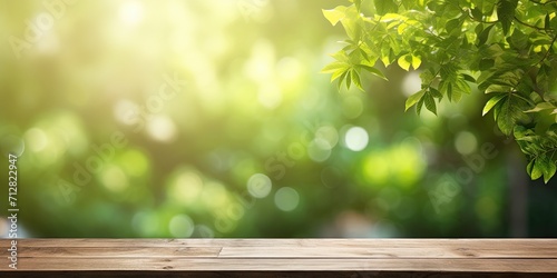 Wooden plank table top with blurred green tree background, sunlight in garden. Bokeh light in natural setting. Mock up for product display.