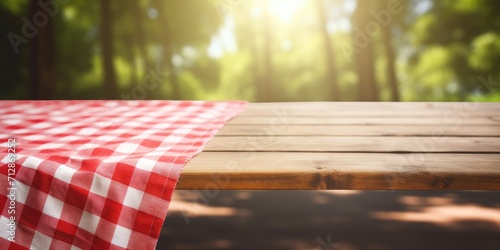 Picnic table with a red checkered towel, empty space, and a blurred wooden deck backdrop. Promotion display.