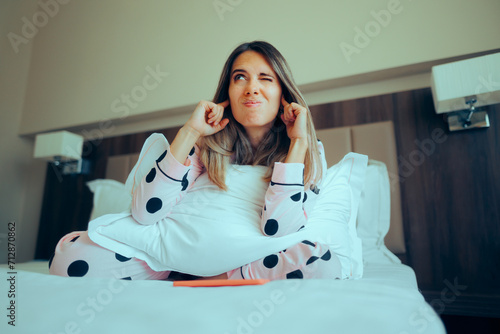 Woman Sitting in Bed Covering her Ears Hearing a Noise. Stressed woman living in an apartment below noisy people 