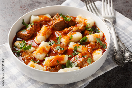 Homemade traditional Polish potato dumplings kopytka served with meat stew close-up in a plate on the table. Horizontal