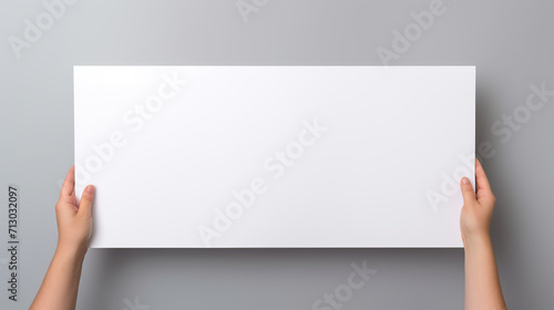 Human hand holding a white board. White blank sheet of paper in hands. Isolated on grey background. Can use for Promotion purpose or Advertising banner.