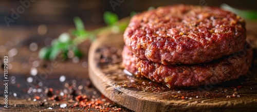 Round ground beef portioned beef patty made from beef mince on a wooden board Hamburger meat seasoned and ready for a barbecue Spices and condiments for a grill Homemade burger recipe Prepared