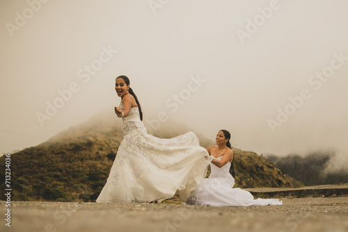 Retrato de una pareja de recién casados caminando al aire libre mientras llevan sus vestidos de novia y sonríen.