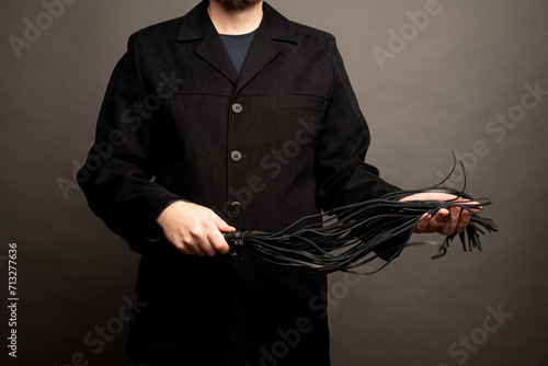 male dominant holds a leather whip Flogger for hard BDSM sex with spanking