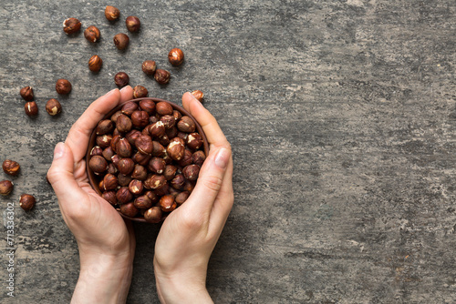 Woman hands holding a wooden bowl with hazelnut nuts. Healthy food and snack. Vegetarian snacks of different nuts