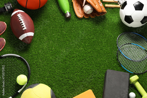 Frame made of different sports equipment on green grass, flat lay. Space for text