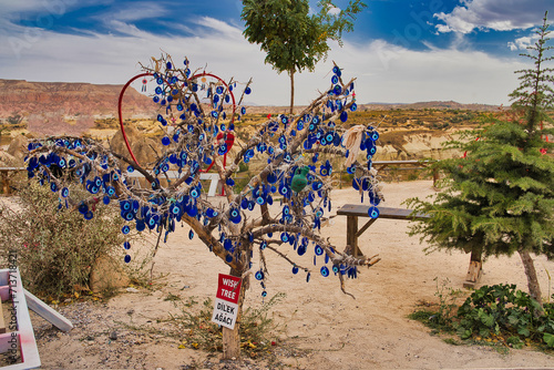 A Wish Tree or Dilek Agaci in Turkish with evil eye pendants to ward off negative energy and fulfil one's desires at the Pigeon Valley Panoramic point near Goreme,Cappadocia Region, Turkey