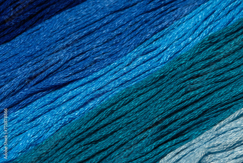 Tło z niebieskich sznurków w różnych odcieniach ulozonych ukośnie z bliska, makro struktura włóczki do szycia 