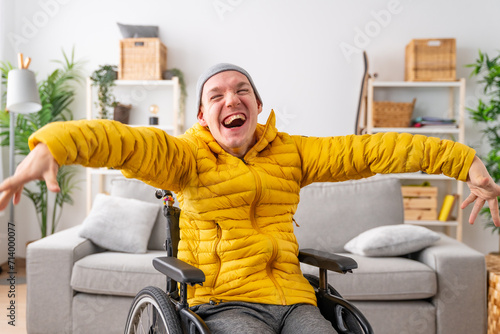 Happy disabled man in wheelchair laughing at camera at home