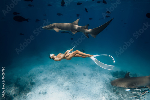 Woman swimming with sharks in a tropical sea in the Maldives.