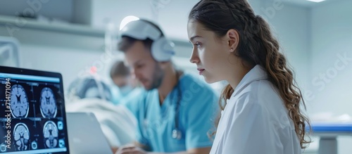 Doctor using laptop to analyze live data from brain waves scanning device during girl's procedure.