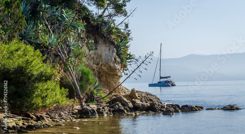 Beach in park around Mon Repos villa in Corfu town with sailing yacht visible