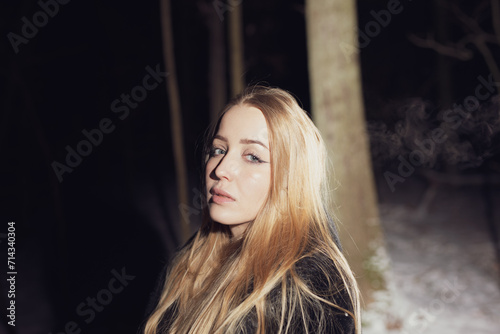 Young blond Woman with black dress in the wood at an snowstorm in deep winter at berlin forrest