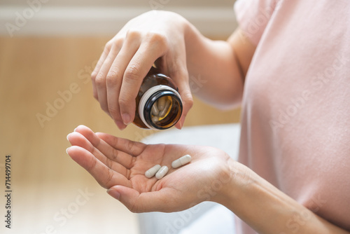Sick ill asian young woman, girl hold tablet pill on hand pour capsule from medication bottle, painkiller medicine from stomach pain, head ache, pain for treatment, take drug or vitamin, health care.