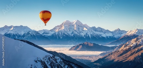  a hot air balloon flying in the sky over a mountain range with snow covered mountains in the foreground and a blue sky with a few clouds in the foreground.