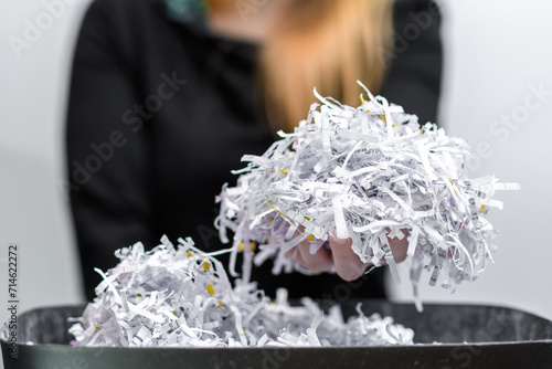 Kobieta trzyma w dłoni makulaturę, zniszczone dokumenty biurowe